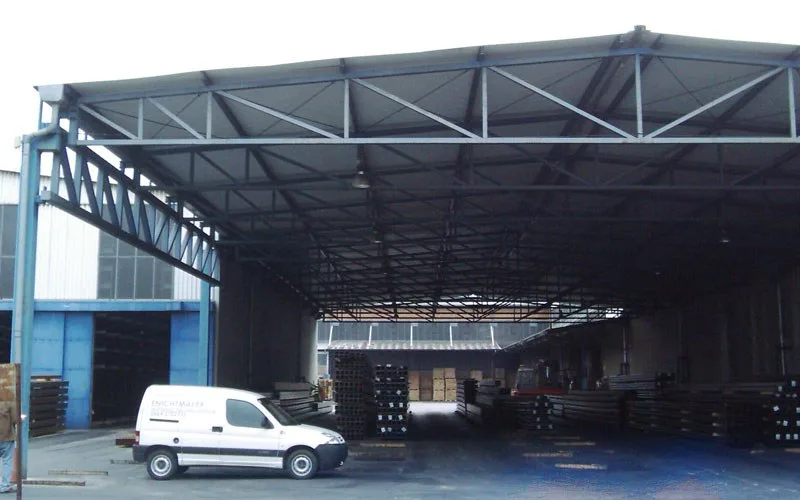 Offene Stahlhalle, davor ein weißer Firmenwagen