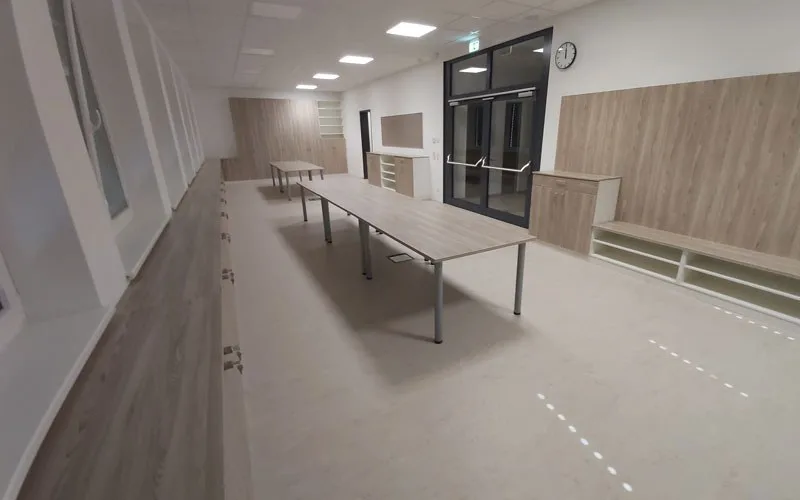 Heller Innenraum mit langem Tisch, Holzverkleidung und Glastür
